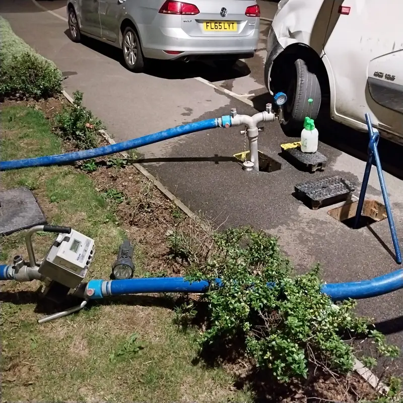 Temporary overland water supply pipe with a standpipe and meter beside a residential road